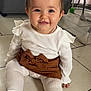 baby, child, smiling, indoor, floor, white_clothing, brown_skirt, hair_bow, tights, cute, sitting, portrait, happy, person, infant, tiled_floor, fashion, accessory, young_child, headwear