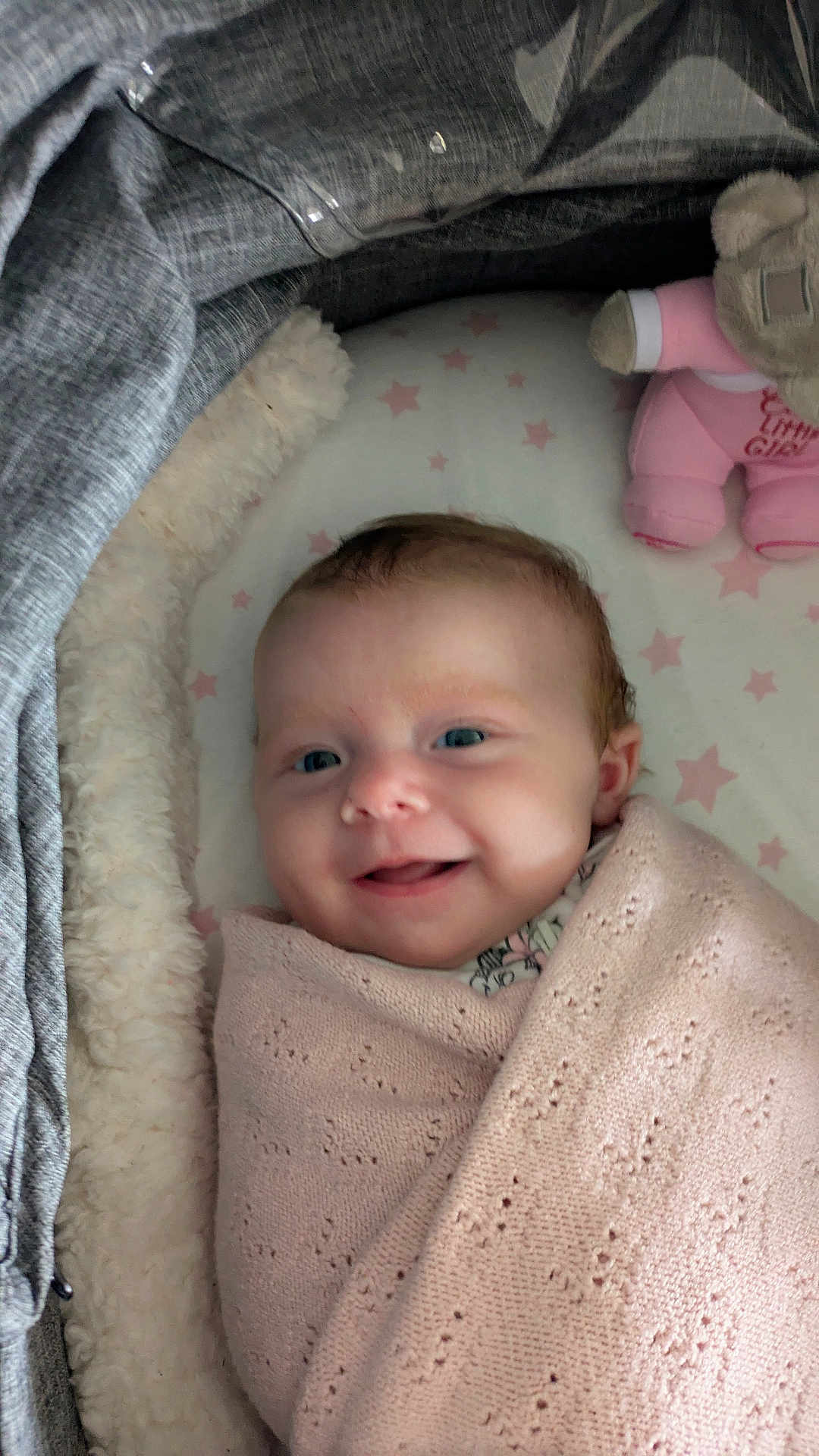 Poppy joined the competition — help win amazing prizes! baby, blanket, smiling, infant, face, soft_toy, teddy_bear, pink, gray, bassinet, fabric, pattern, star, sleeping_area, cute, child, portrait, wrapped, cozy, indoor