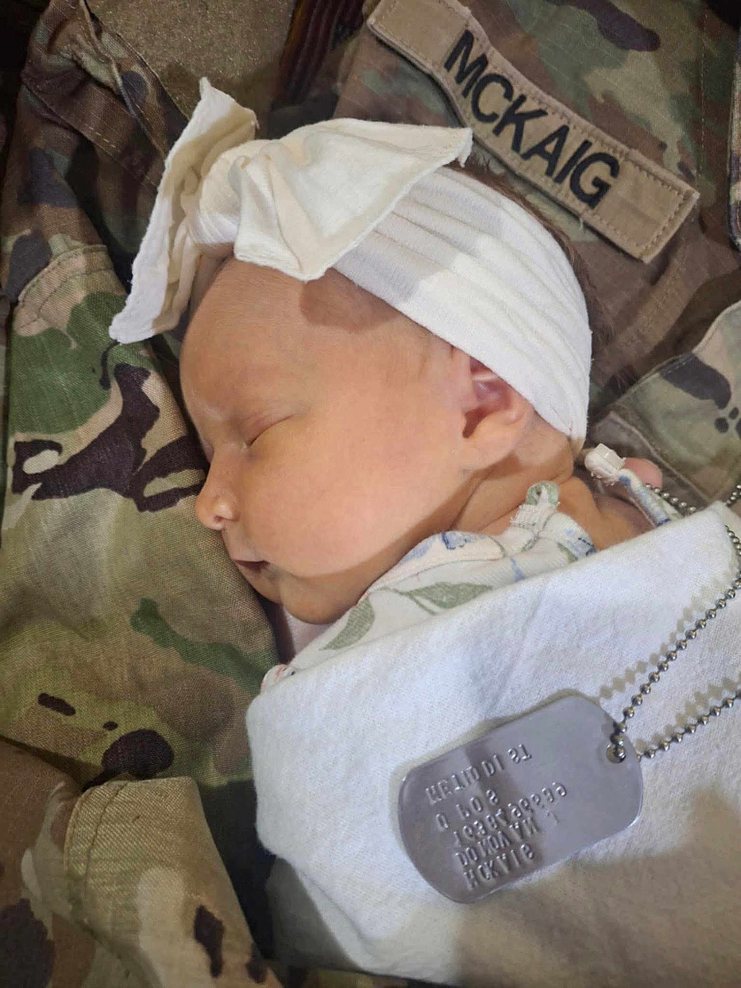 Maddilynn joined the competition — help win amazing prizes! baby, sleeping, headband, white_cloth, military_uniform, camouflage, dog_tag, name_patch, infant, peaceful, close_up, portrait, person, soft_light, newborn, resting, cute, head, skin, ear