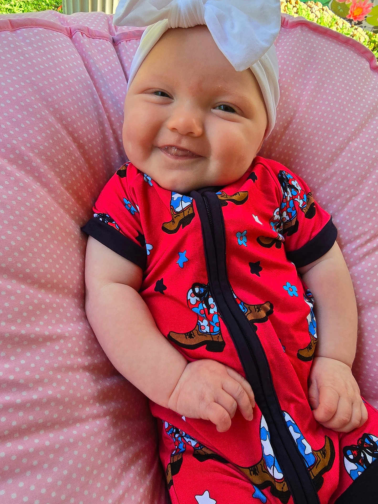 Remmie Kate is registered to the contest to win money with this photo: baby, smiling, headband, red_clothing, cushion, pink, polka_dot, indoor, happy, infant, cute, child, portrait, hands, face, patterned_clothing, relaxed, seated, closeup, light