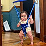 Mizuki joined the competition — help win amazing prizes! baby, child, indoor, wooden_floor, blue_jumper, harness, smiling, drool, doorway, wall_socket, wooden_trim, flooring, person, cute, infant, legs, barefoot, clothing, home, play