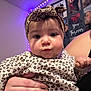 baby, child, infant, leopard_print, headband, clothing, hand, nails, person, portrait, indoor, purple_lights, wall_art, photo_collage, face, cute, expression, holding, skin, young