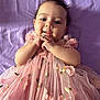 baby, infant, child, pink_dress, floral_pattern, smiling, hands_clasped, purple_blanket, cute, portrait, lying_down, adorable, face, young_child, happy, tulle, soft_lighting, indoor, close_up, person