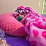 baby, blanket, pillow, pacifier, headband, bed, indoor, child, cozy, curious, pink, heart_pattern, soft_texture, resting, person, face, young_child, candid, comfort, cute