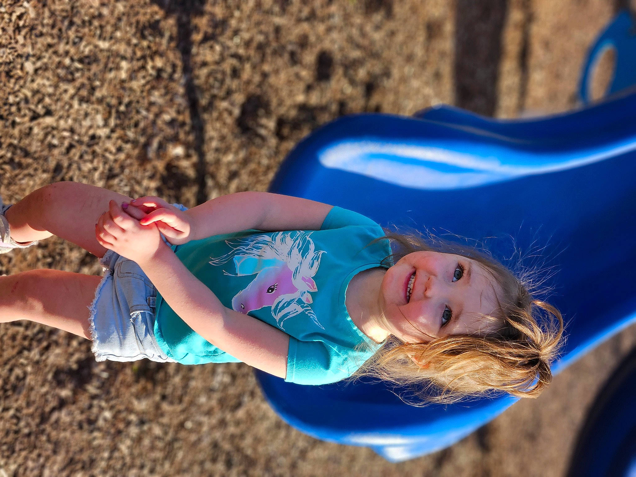 Freya is registered to the contest to win money with this photo: arm, blond, blue, child, electric_blue, face, fun, grass, happy, human_leg, joy, leisure, outdoor_play_equipment, people_in_nature, person, play, playground, recreation, smile, thigh