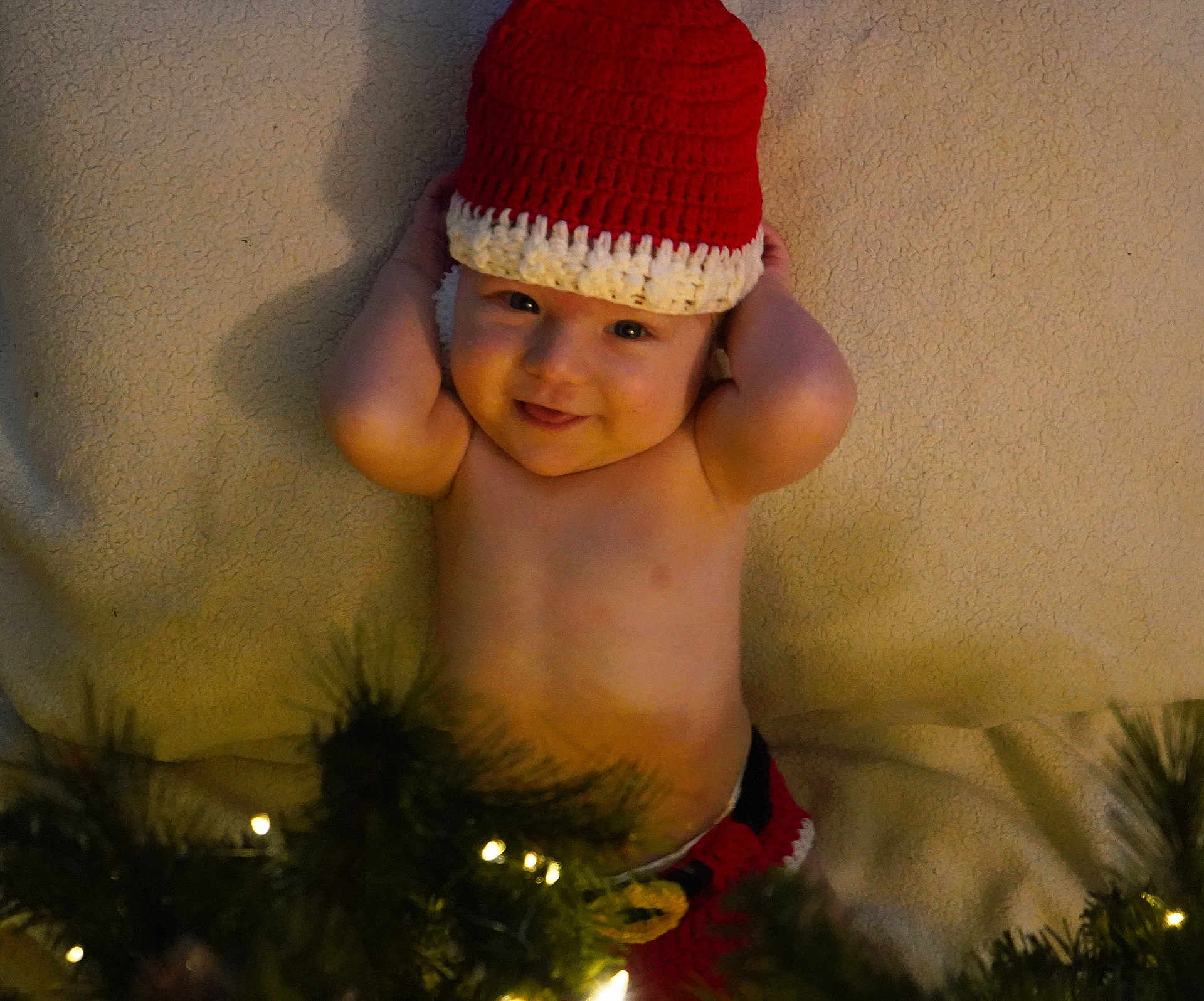 Pauly joined the competition — help win amazing prizes! baby, child, smiling, hat, crochet, blanket, christmas_lights, holiday, festive, greenery, infant, cute, portrait, laying_down, indoors, warm, happy, toddler, skin, hands