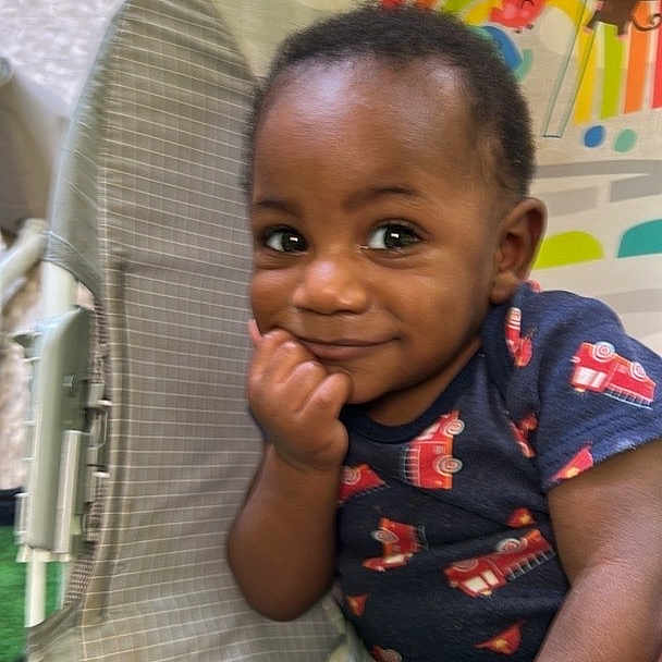Marcel joined the competition — help win amazing prizes! baby, child, infant, smiling, portrait, sitting, bouncer, baby_chair, playroom, rainbow, sun_decoration, toy, colorful, indoors, clothing, dark_skin, short_hair, hand_on_chin, happy, candid