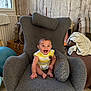 baby, child, smiling, happy, armchair, gray, plush, indoor, cozy, wooden_wall, window, floor, home, cushion, sitting, person, infant, clothing, furniture, radiator