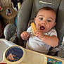Pablo participe au concours pour gagner de l'argent avec cette photo : baby, high_chair, biscuit, toy, indoor, child, curious, cute, person, playful, feeding, seat, infant, expression, hands, face, clothing, home, early_childhood, fun