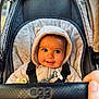 Otis is registered to the contest to win money with this photo: baby, child, stroller, hooded_jacket, smile, cute, face, infant, outdoor, hand, seat, straps, warm_clothing, plush, comfort, person, closeup, portrait, expression, baby_accessory
