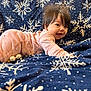 baby, blanket, blue_blanket, child, christmas_ornaments, cozy, cute, decorations, face, festive, hair, happy, holiday_theme, indoor, infant, lying_down, pajamas, pink_clothing, smiling, snowflake_pattern