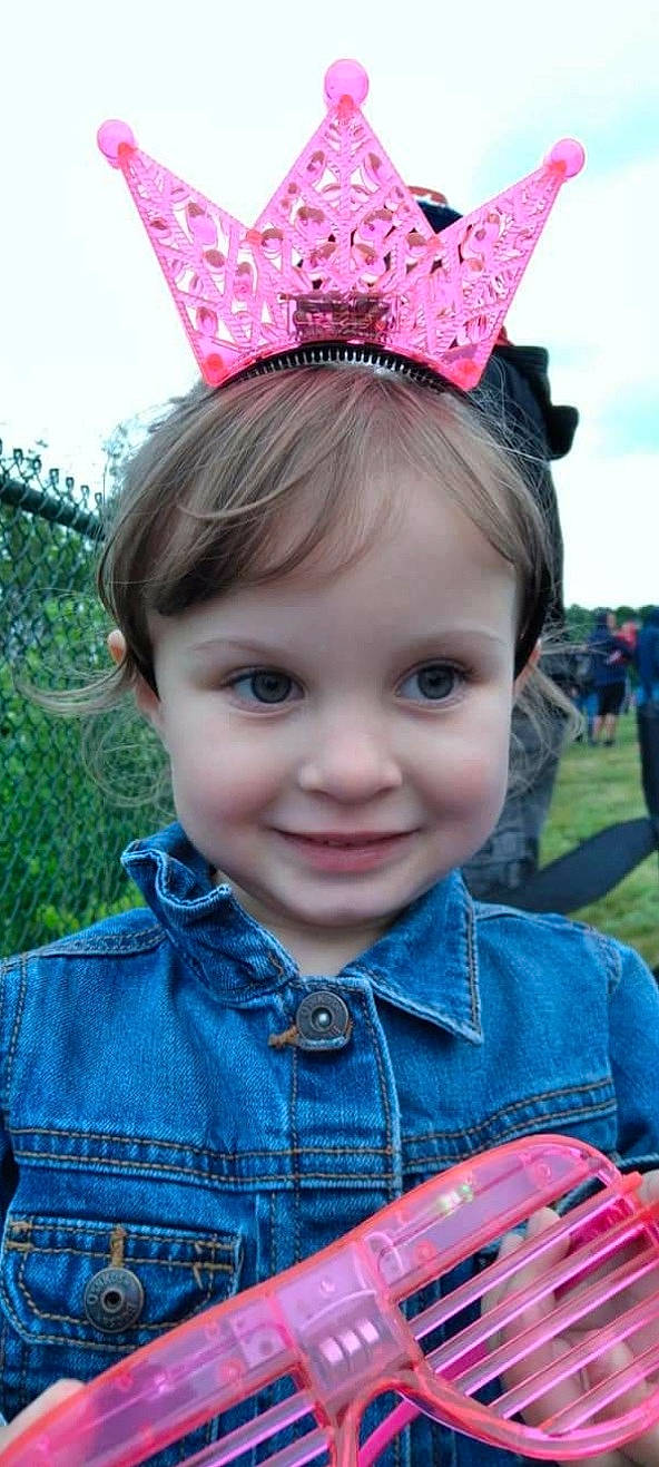 Zelda is registered to the contest to win money with this photo: blue, face, fun, grass, happy, head, headgear, joy, leaf, mammal, organ, party_hat, person, pink, plant, skin, sky, smile, textile, toddler