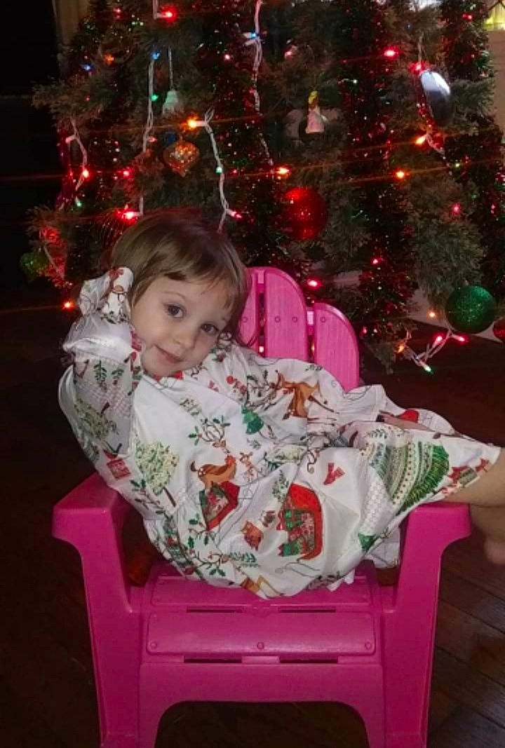 Zelda joined the competition — help win amazing prizes! beauty, christmas, christmas_decoration, christmas_ornament, christmas_tree, event, face, facial_expression, fun, happy, holiday, human_body, lap, organ, person, red, smile, snapshot, standing, toddler