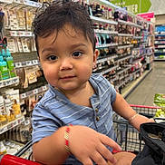 Evan joined the competition — help win amazing prizes! toddler, child, shopping_cart, supermarket, aisle, beauty_products, bracelet, blue_shirt, curly_hair, cute, face, person, retail, store, grocery, young_child, casual_clothing, indoors, playful, portrait