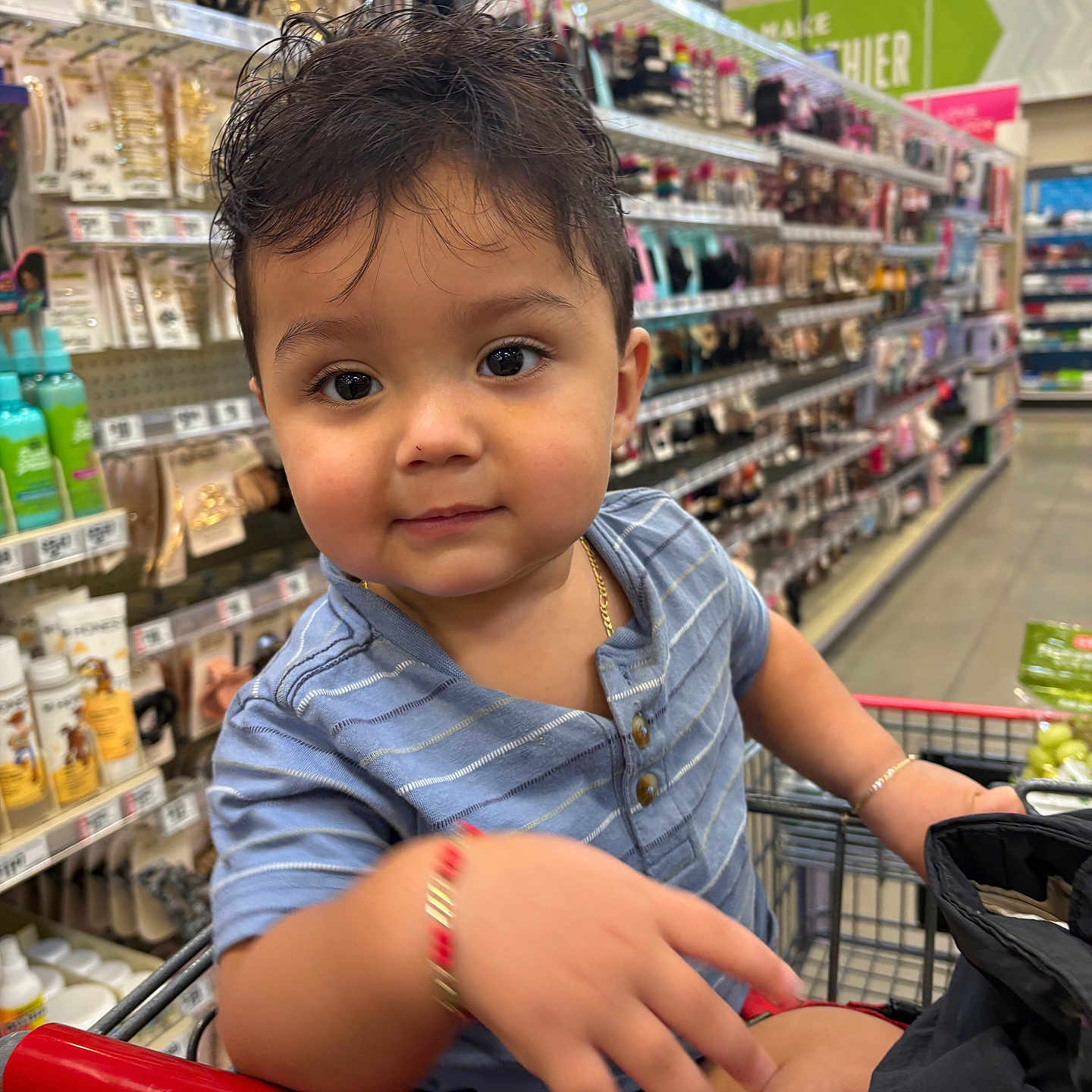 Evan joined the competition — help win amazing prizes! toddler, child, shopping_cart, supermarket, aisle, beauty_products, bracelet, blue_shirt, curly_hair, cute, face, person, retail, store, grocery, young_child, casual_clothing, indoors, playful, portrait