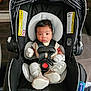 Javion joined the competition — help win amazing prizes! baby, infant, car_seat, safety_harness, mittens, slippers, black, gray, fabric, cushion, child, person, indoors, cute, newborn, seat, warning_label, soft, portrait, secure