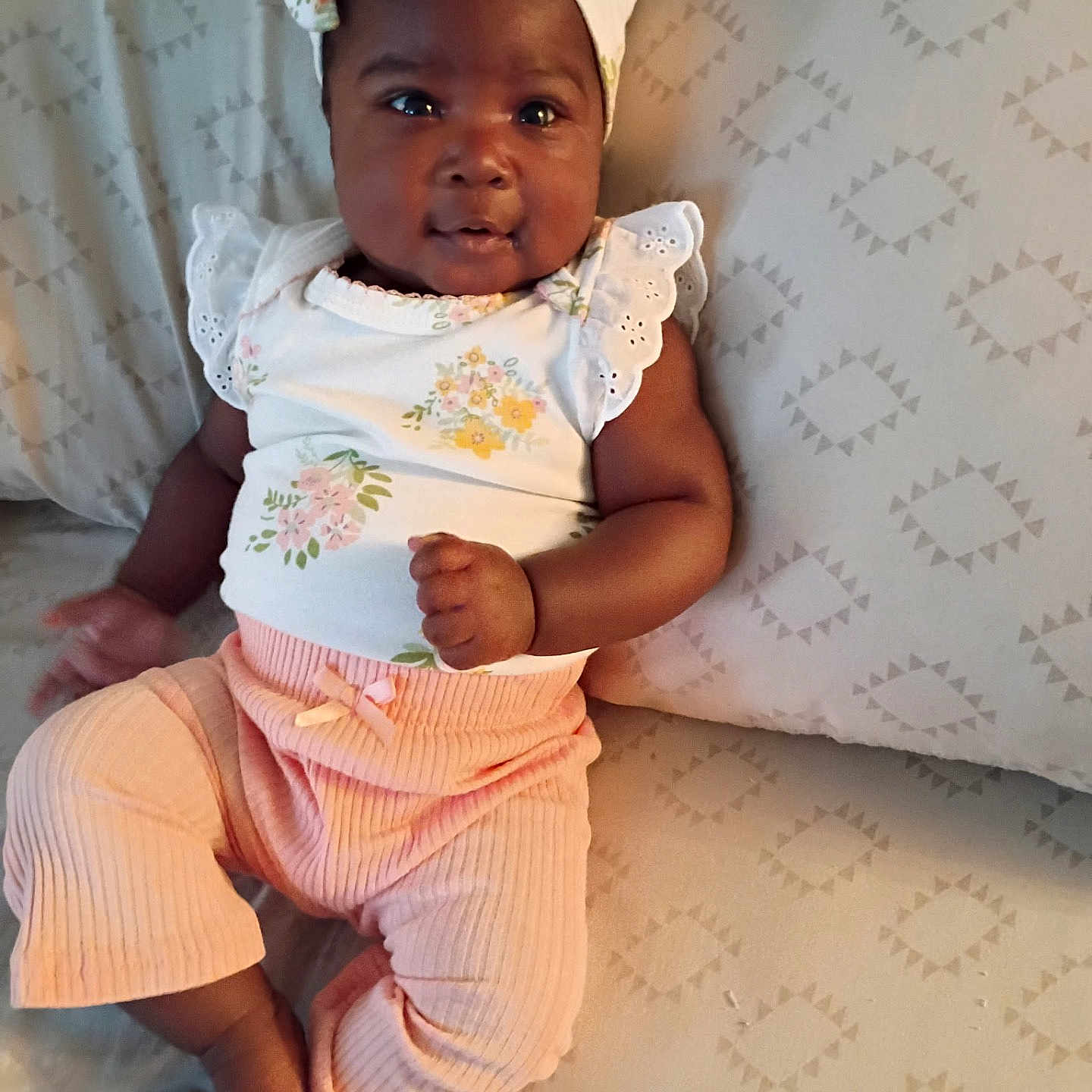 Jalaisha is registered to the contest to win money with this photo: baby, child, closeup, clothing, comfortable, cushion, cute, fabric, floral, happy, headwrap, indoor, infant, patterned, person, pink_pants, portrait, sitting, smiling, soft_lighting