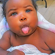 Jalaisha is registered to the contest to win money with this photo: baby, infant, tongue_out, blanket, cute, playful, child, skin, hand, face, expression, indoor, curly_hair, pout, adorable, young_child, wrapped, soft_texture, closeup, portrait