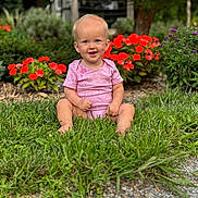 Ava is registered to the contest to win money with this photo: baby, child, grass, flowers, pink_clothing, outdoor, garden, greenery, smiling, sitting, nature, plants, happy, face, portrait, infant, sunlight, daylight, cute, young