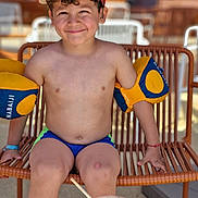 Zakarya participe au concours pour gagner de l'argent avec cette photo : beverage, boy, casual, chair, child, curly_hair, drink, floaties, happy, outdoor, playful, portrait, red_cap, relaxation, seat, smiling, summer, sunny, swimwear, water_fun