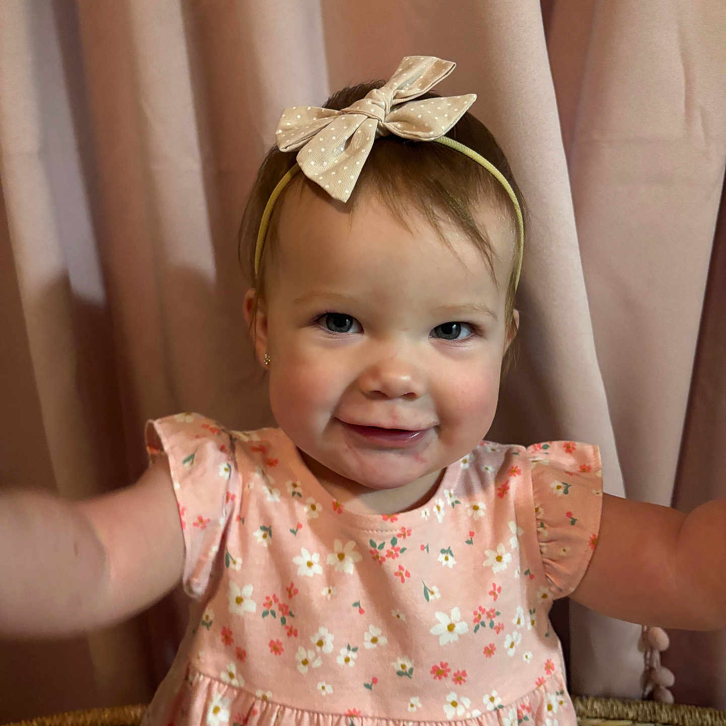 Lillian is registered to the contest to win money with this photo: arm, baby, bow, child, curtain, cute, dress, face, fashion, floral_pattern, happy, headband, indoors, person, pink, portrait, skin, smiling, toddler, young