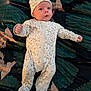 baby, infant, onesie, hat, blanket, leaf_pattern, animal_print, lying_down, curious, fist, cute, sleepwear, child, portrait, indoor, soft_lighting, face, headwear, newborn, resting