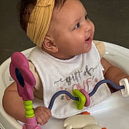 Taliyah is registered to the contest to win money with this photo: baby, baby_walker, bib, child, closeup, clothing, cute, face, hand, happy, headband, indoor, infant, person, play, seated, skin, smiling, toy, young_child