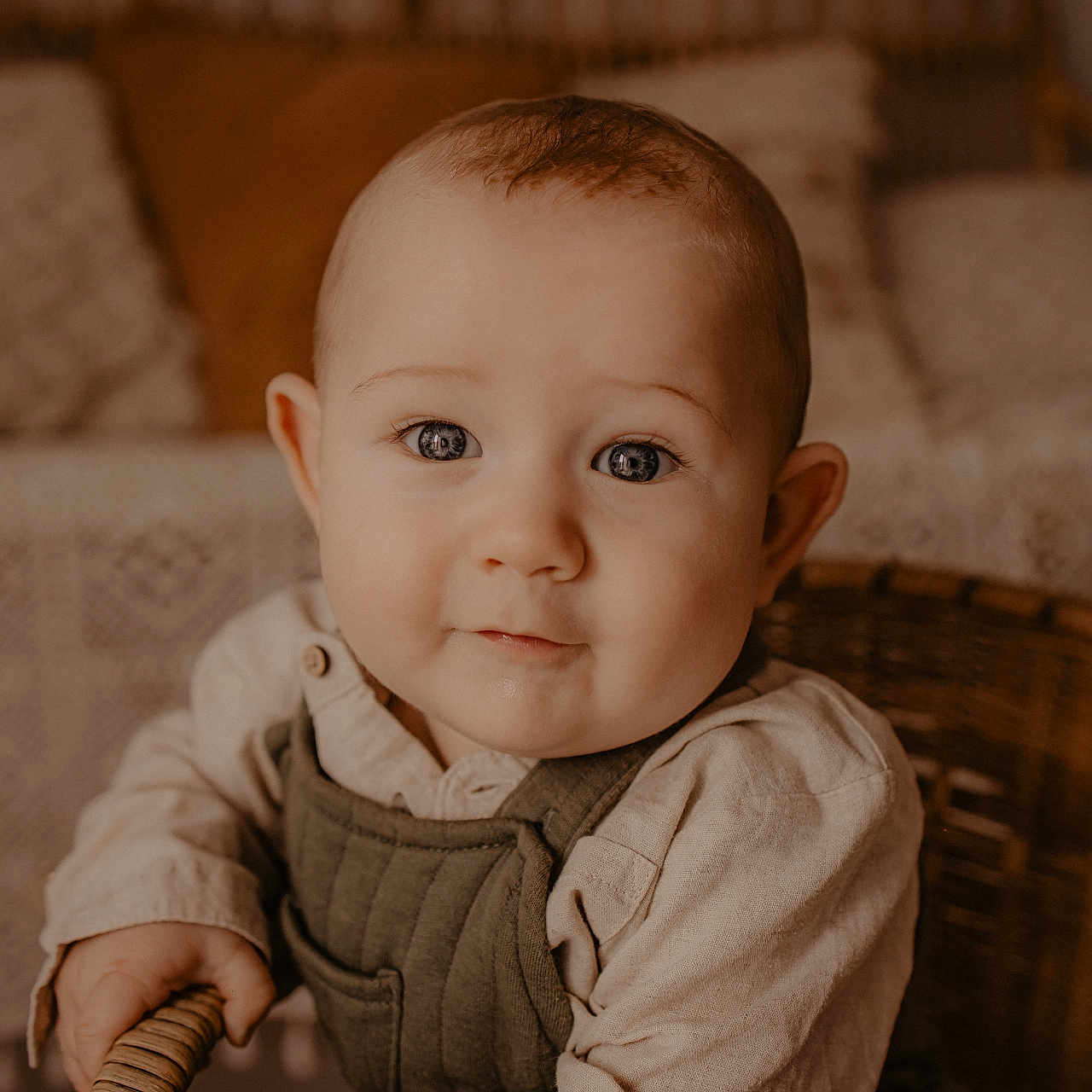 Eden a rejoint le concours — aidez-le/la à gagner de superbes lots ! baby, chair, child, clothing, cushion, cute, eyes, face, hands, home_interior, indoor, infant, overalls, pillow, portrait, shirt, sitting, smile, warm_tones, wicker