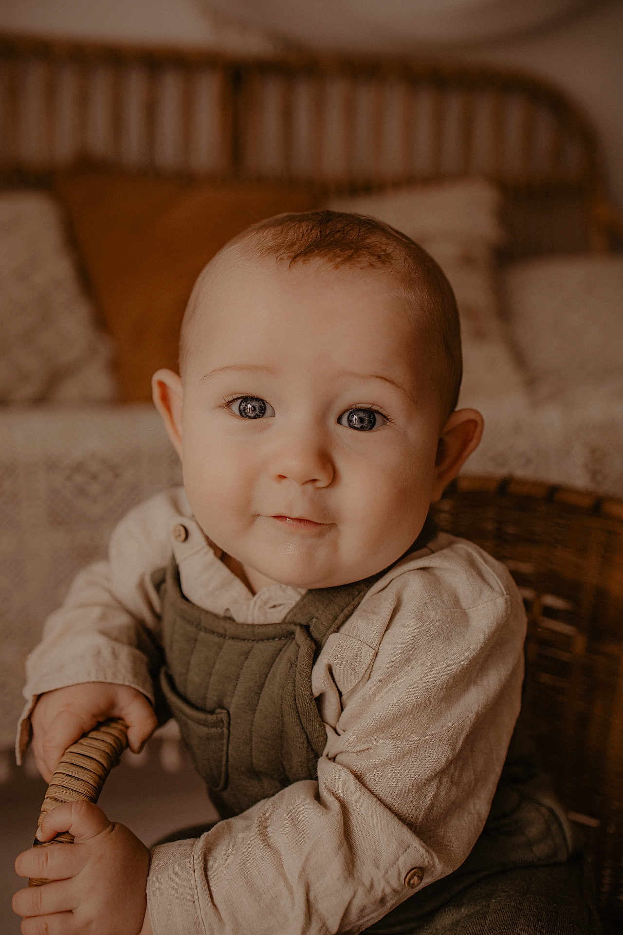 Eden a rejoint le concours — aidez-le/la à gagner de superbes lots ! baby, child, face, eyes, clothing, overalls, shirt, hands, wicker, chair, cushion, pillow, home_interior, portrait, cute, smile, infant, sitting, warm_tones, indoor