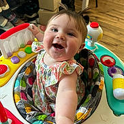 Delainey is registered to the contest to win money with this photo: baby, child, smiling, pigtails, activity_center, toy, colorful, indoor, happy, face, person, clothing, flooring, playtime, infant, cute, furniture, patterned, seat, expression