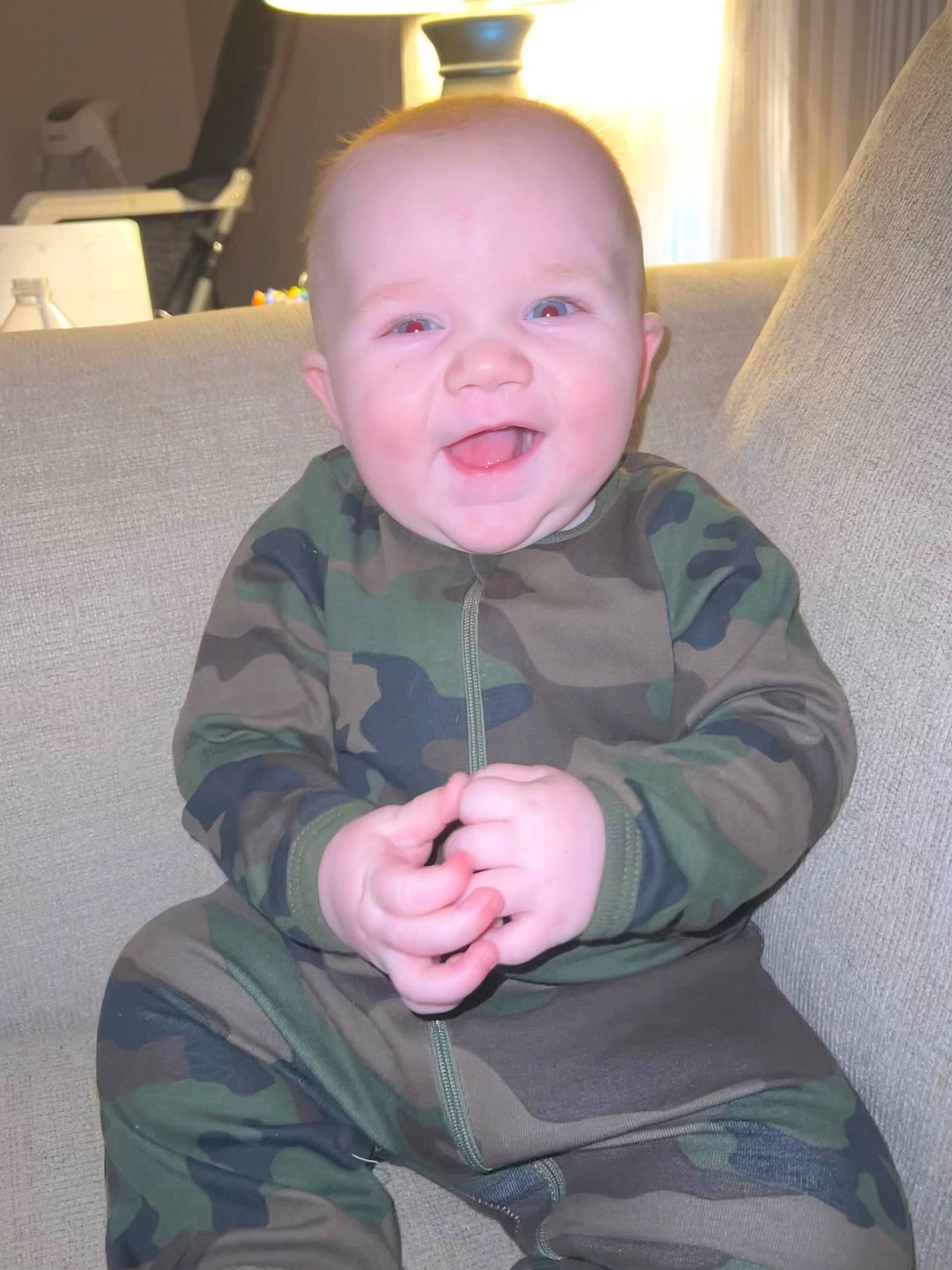 Damien is registered to the contest to win money with this photo: baby, baby_toddler_clothing, camouflage, cheek, comfort, eye, gesture, happy, head, human_body, iris, military_camouflage, nose, person, room, sitting, skin, sleeve, smile, thumb