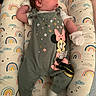 baby, child, clothing, colorful, cushion, cute, indoor, infant, laying_down, lounger, minnie_mouse, mittens, newborn, onesie, person, portrait, rainbow_pattern, resting, sleepwear, soft_toys