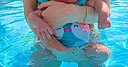 Noelani joined the competition — help win amazing prizes! baby, child, person, swimming_pool, water, adult, holding, blue_eyes, swimsuit, summer, outdoor, sunlight, reflection, skin, arms, legs, nature, greenery, relaxation, vacation