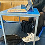 Butterfingers is registered to the contest to win money with this photo: student, classroom, desk, chair, backpack, tablet, textbook, sneakers, legs, hand, tights, blue_table, carpet, floor, footwear, schoolbag, casual_clothing, study_materials, wooden_cabinet, plastic_chair