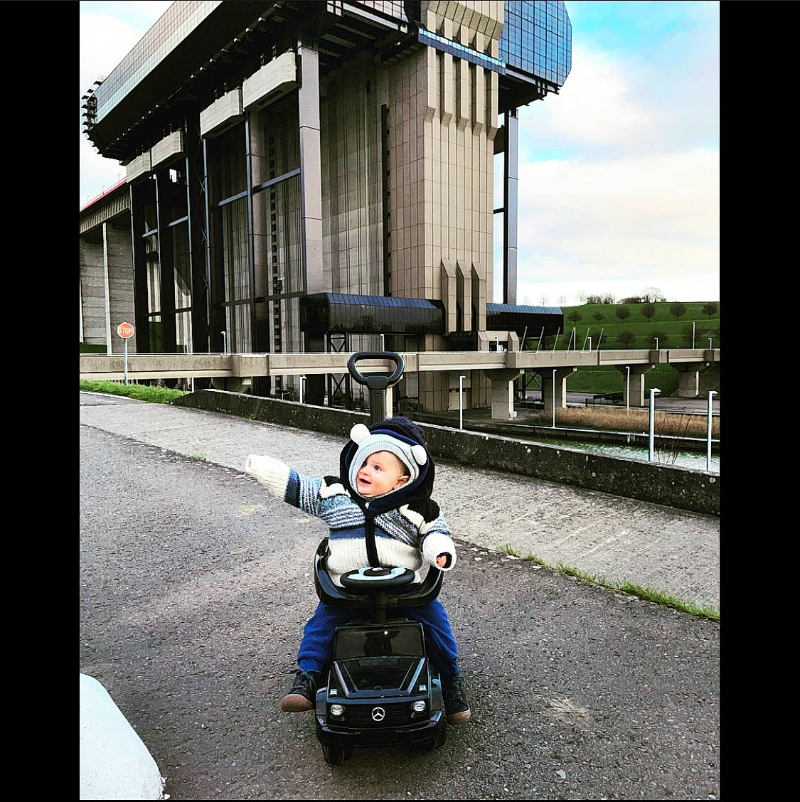 Iago a rejoint le concours — aidez-le/la à gagner de superbes lots ! asphalt, automotive_design, automotive_exterior, automotive_lighting, baby, baby_carriage, baby_products, building, headlamp, headwear, helmet, mode_of_transport, motor_vehicle, person, road, rolling, sky, tire, toddler, travel