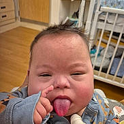 Ronan joined the competition — help win amazing prizes! baby, button, child, clothing, crib, door, expression, face, hair, hand, indoor, jacket, medical_tube, person, playful, room, sleeve, tongue, tongue_out, wooden_floor