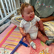 Ronan joined the competition — help win amazing prizes! baby, child, infant, smiling, tongue_out, medical_tube, socks, patchwork_quilt, striped_pillow, crib, carpet, adult, green_shirt, cartoon_fish, indoor, room, sitting, happy, person, cute