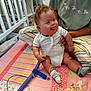 Ronan joined the competition — help win amazing prizes! baby, infant, smiling, tongue_out, medical_tube, quilt, striped_pillow, socks, indoor, carpet, crib, sitting, person, adult, hand, room, shelf, clothing, happy, home