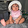 baby, child, infant, hat, pink_bib, sitting, indoors, toes, hand, foot, blanket, curious, wide_eyes, soft_texture, playful, person, young_child, clothing, cute, portrait