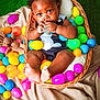 Cotie is registered to the contest to win money with this photo: baby, child, basket, plastic_eggs, colorful, plush_toy, bunny, curious, chewing, green_background, blanket, soft_texture, cute, indoors, playful, infant, feet, clothing, portrait, happy