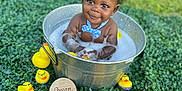 Cotie joined the competition — help win amazing prizes! baby, child, bucket, bath, bubbles, rubber_duck, toy, greenery, grass, outdoor, smiling, cute, water, playful, blue_bow_tie, infant, seven_months, happy, face, portrait