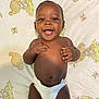 Cotie is registered to the contest to win money with this photo: baby, smiling, diaper, infant, lying_down, blanket, teddy_bear_pattern, butterfly_pattern, cute, happy, child, skin, face, hands, expression, closeup, indoors, newborn, person, portrait