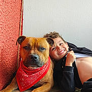 Voyou a rejoint le concours — aidez-le/la à gagner de superbes lots ! dog, child, red_bandana, smiling, curly_hair, indoor, wall, wood_floor, portrait, friendship, playing, happy, pet, casual_clothing, brown_dog, boy, closeup, relaxing, companionship, cute