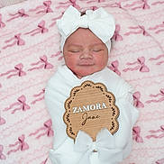 Zamora joined the competition — help win amazing prizes! newborn, baby, infant, sleeping, white_bow, headband, blanket, pink_blanket, bows, soft_texture, wooden_sign, name_sign, wrapped, portrait, cute, peaceful, child, indoors, cozy, resting