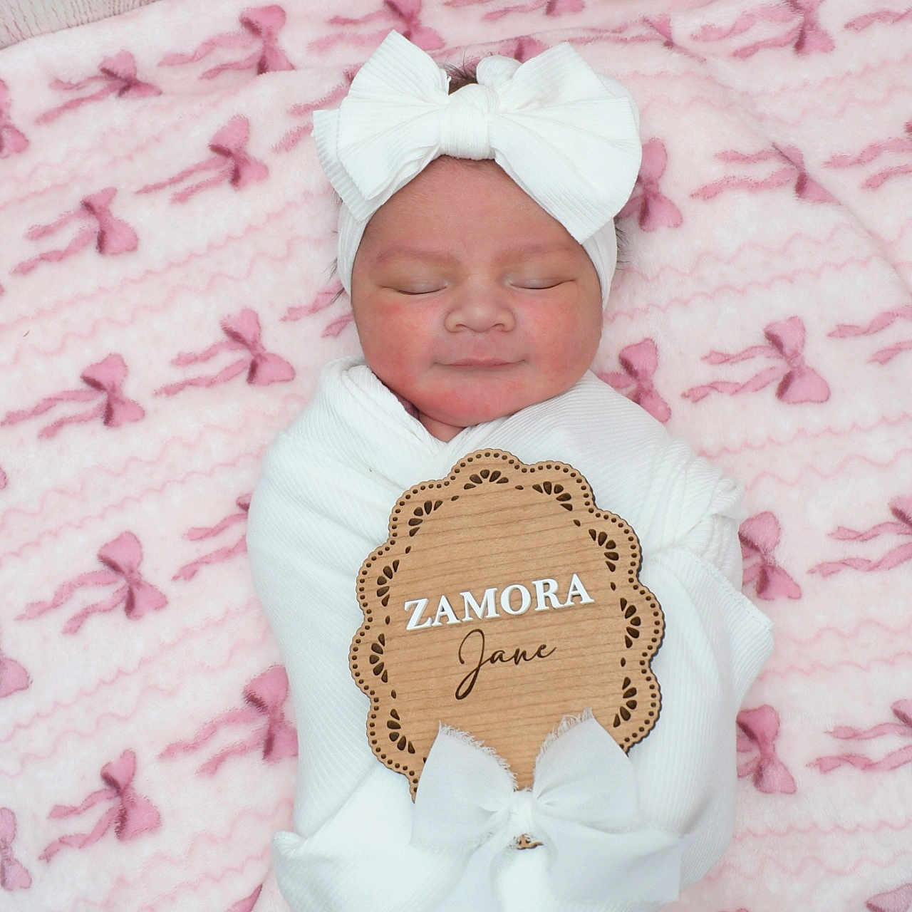 Zamora joined the competition — help win amazing prizes! newborn, baby, infant, sleeping, white_bow, headband, blanket, pink_blanket, bows, soft_texture, wooden_sign, name_sign, wrapped, portrait, cute, peaceful, child, indoors, cozy, resting