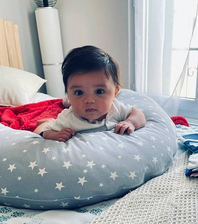 Lucas participe au concours pour gagner de l'argent avec cette photo : arm, baby, baby_products, baby_toddler_clothing, bedding, child, comfort, curtain, eye, flooring, hairstyle, happy, head, linens, paper_towel, person, sitting, skin, sleeve, toddler