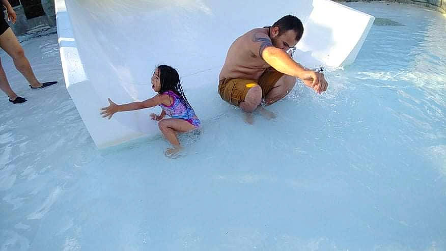 Skylar is registered to the contest to win money with this photo: barefoot, child, event, flooring, freezing, fun, games, happy, leisure, person, play, recreation, shorts, sitting, t_shirt, thigh, toddler, vacation, water, wave