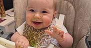 Riley joined the competition — help win amazing prizes! baby, bib, child, cute, face, feeding, food, fun, green_food, hand, happy, high_chair, indoor, kitchen, messy, person, seat, smiling, table, young