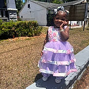 Jailah is registered to the contest to win money with this photo: child, girl, dress, purple, pink, outdoor, sunny, smiling, concrete, grass, hedge, blue_sky, shoes, bracelet, hair_bow, cute, happy, portrait, daylight, standing