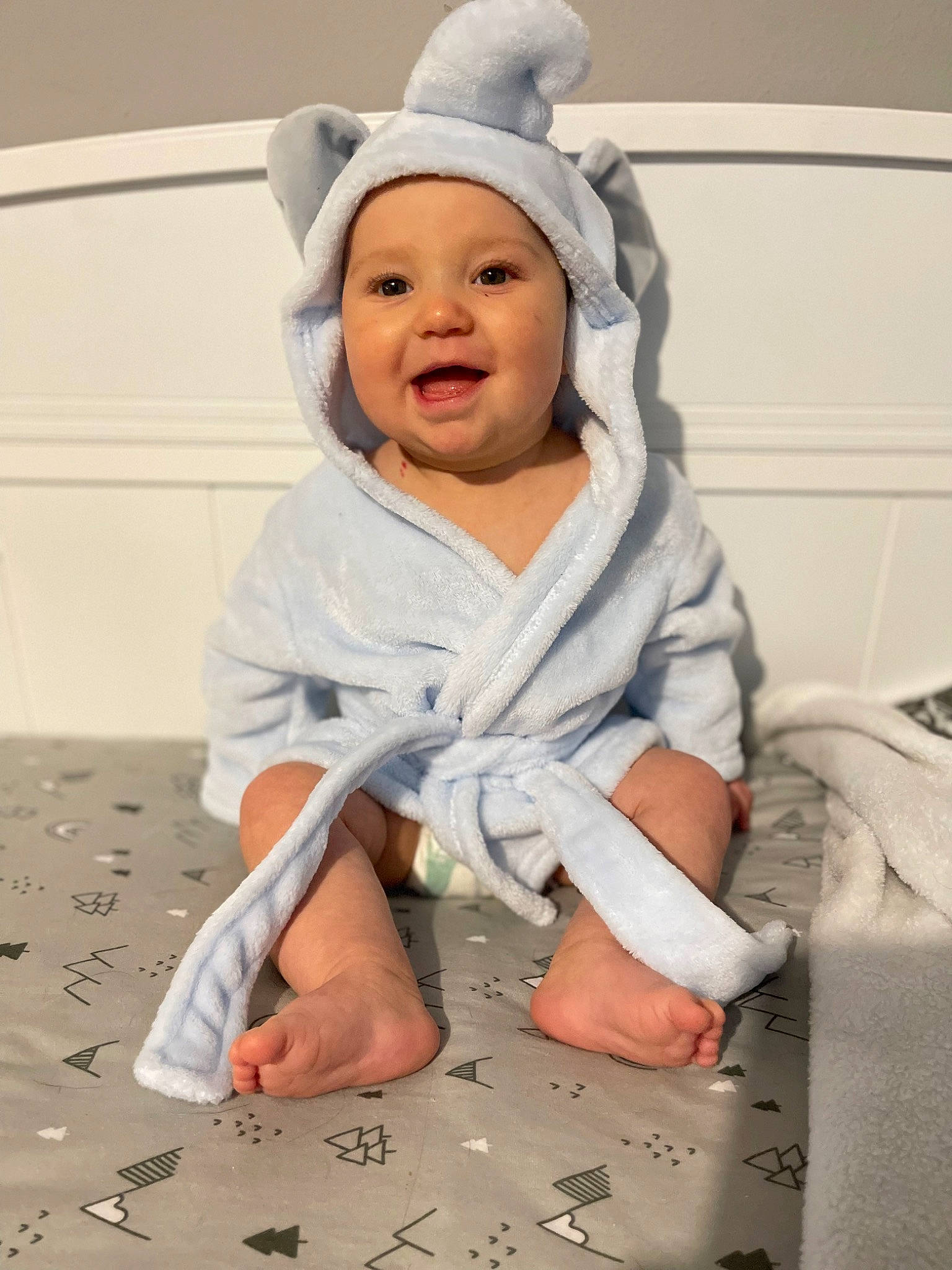 Finley joined the competition — help win amazing prizes! arm, baby, baby_toddler_clothing, cap, child, comfort, face, finger, flooring, gesture, happy, headgear, headwear, human_body, joy, leg, linens, person, sitting, sleeve